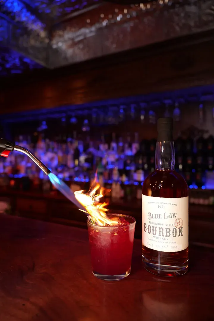Torch flaming cocktail garnish at bar
